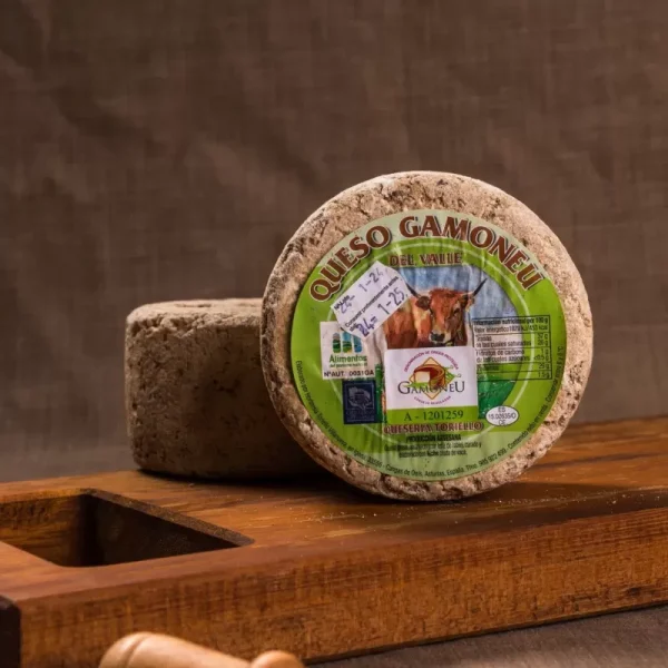 Queso Gamoneu del Valle, con corteza natural y etiquetado, sobre una tabla de madera, ideal para acompañar con vinos o como parte de una tabla de quesos.