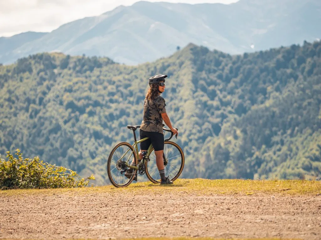 Persona con bicicleta de montaña en un paisaje montañoso, disfrutando de la vista panorámica. Ideal para amantes del ciclismo y la naturaleza.